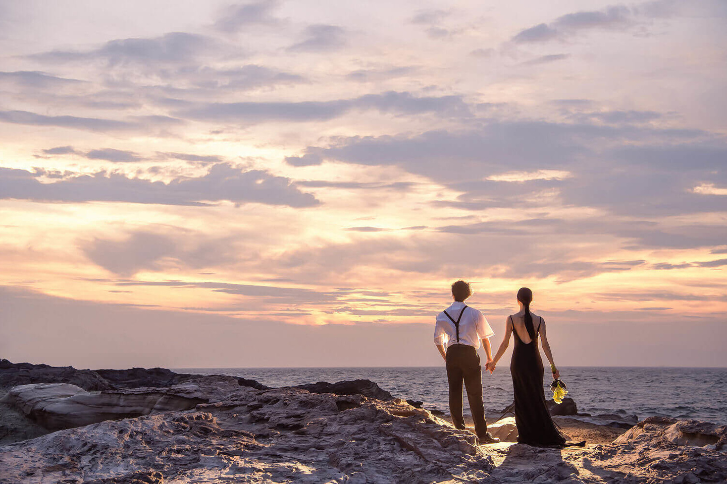 夕焼けの海を見つめる新郎新婦